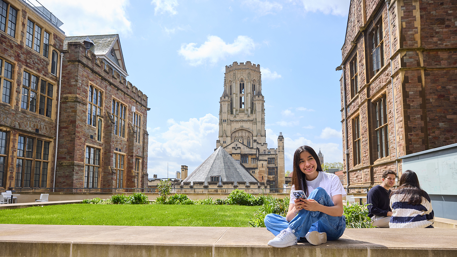 Student sitting on wall with Wills Memorial Building in the background